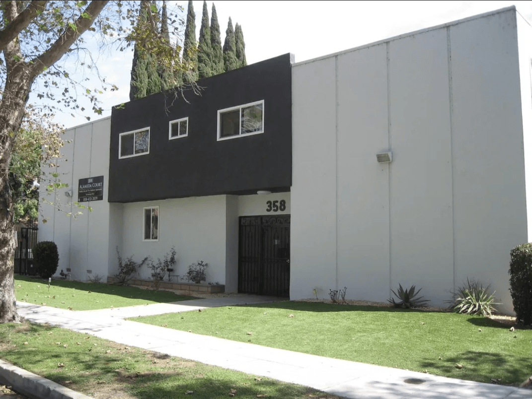 A white building with black trim and windows is numbered 358.